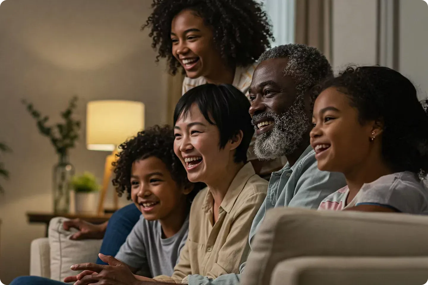 Happy international family watches tv together at home.