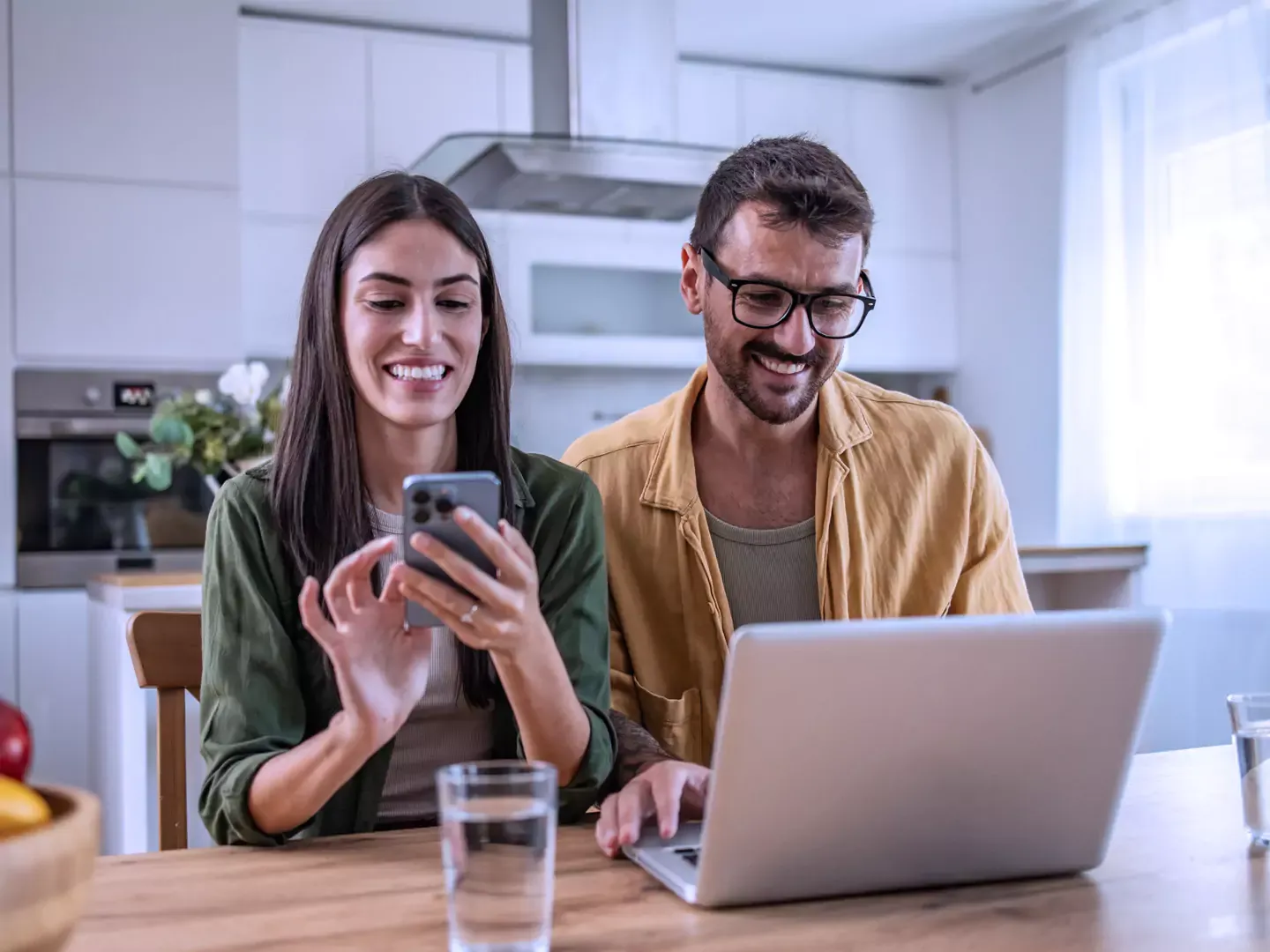 Couple happily enjoying their Internet together, female is using smartphone, male using laptop.