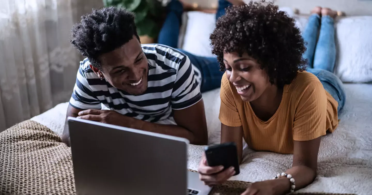 Couple enjoying some internet time on their phone and laptop.