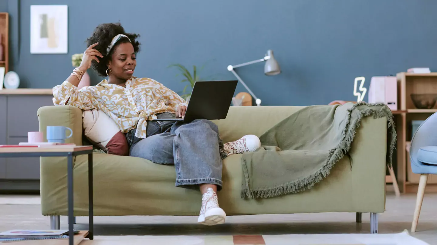 Woman using the internet and lounging on her green sofa in her stylish apartment.