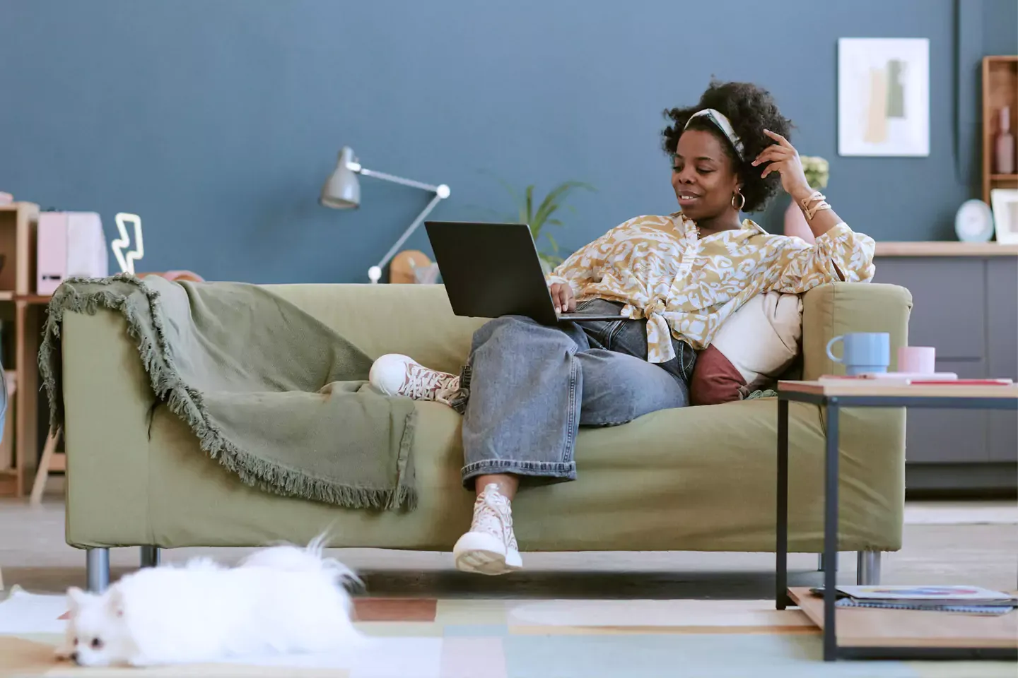 Woman using the internet and lounging on her green sofa in her stylish apartment.