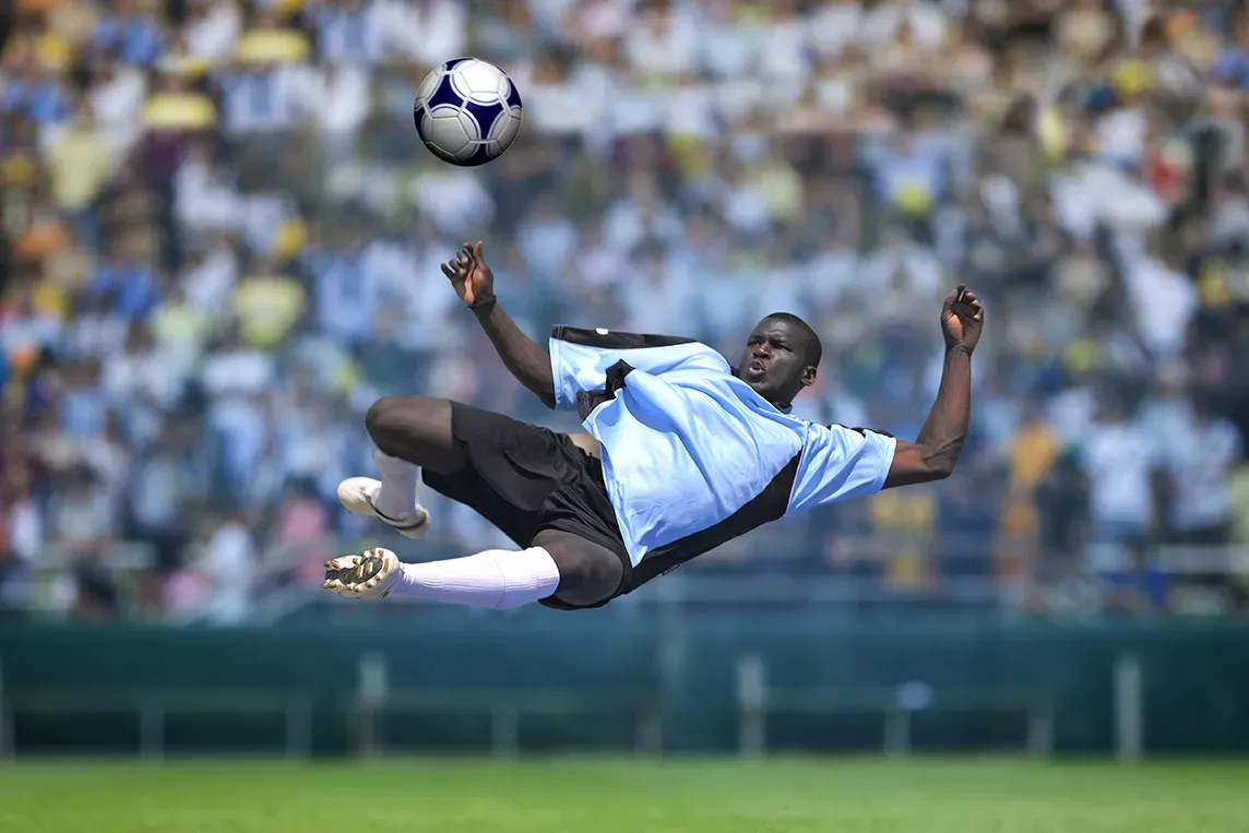 Male soccer player kicks ball into the air