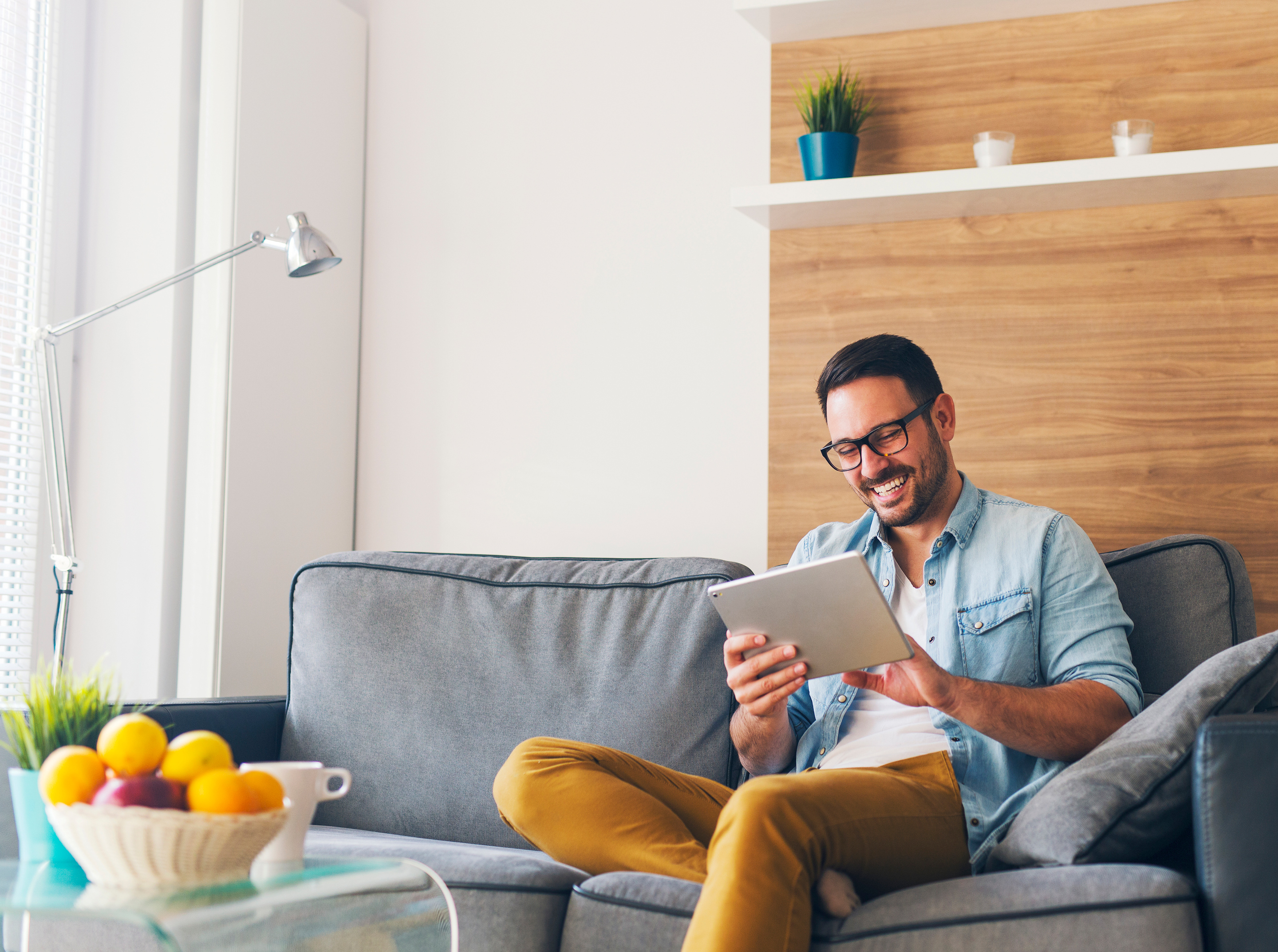 Man on a couch using CenturyLink fiber internet to surf the web on his tablet.
