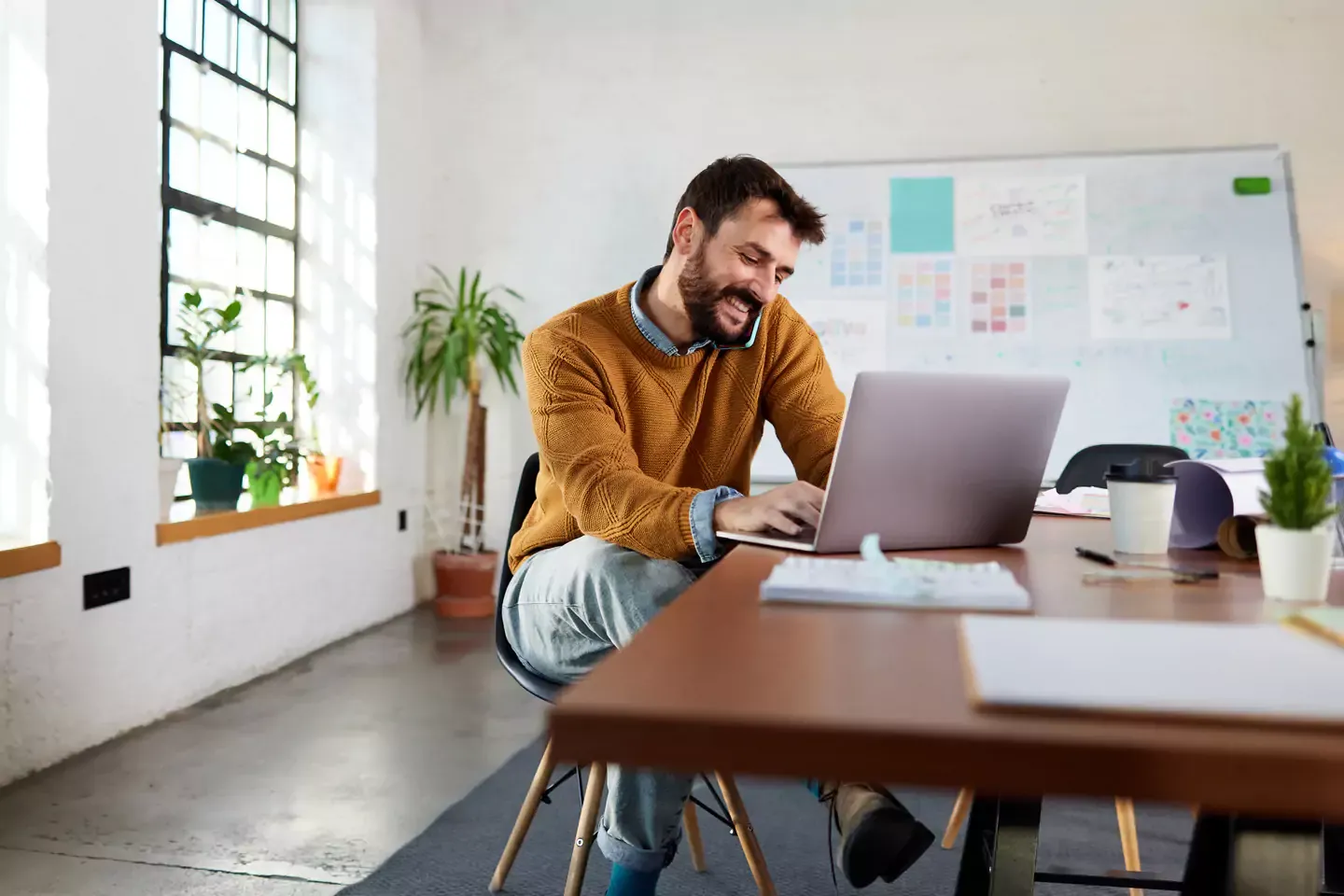 Man in yellow sweater using laptop at the office