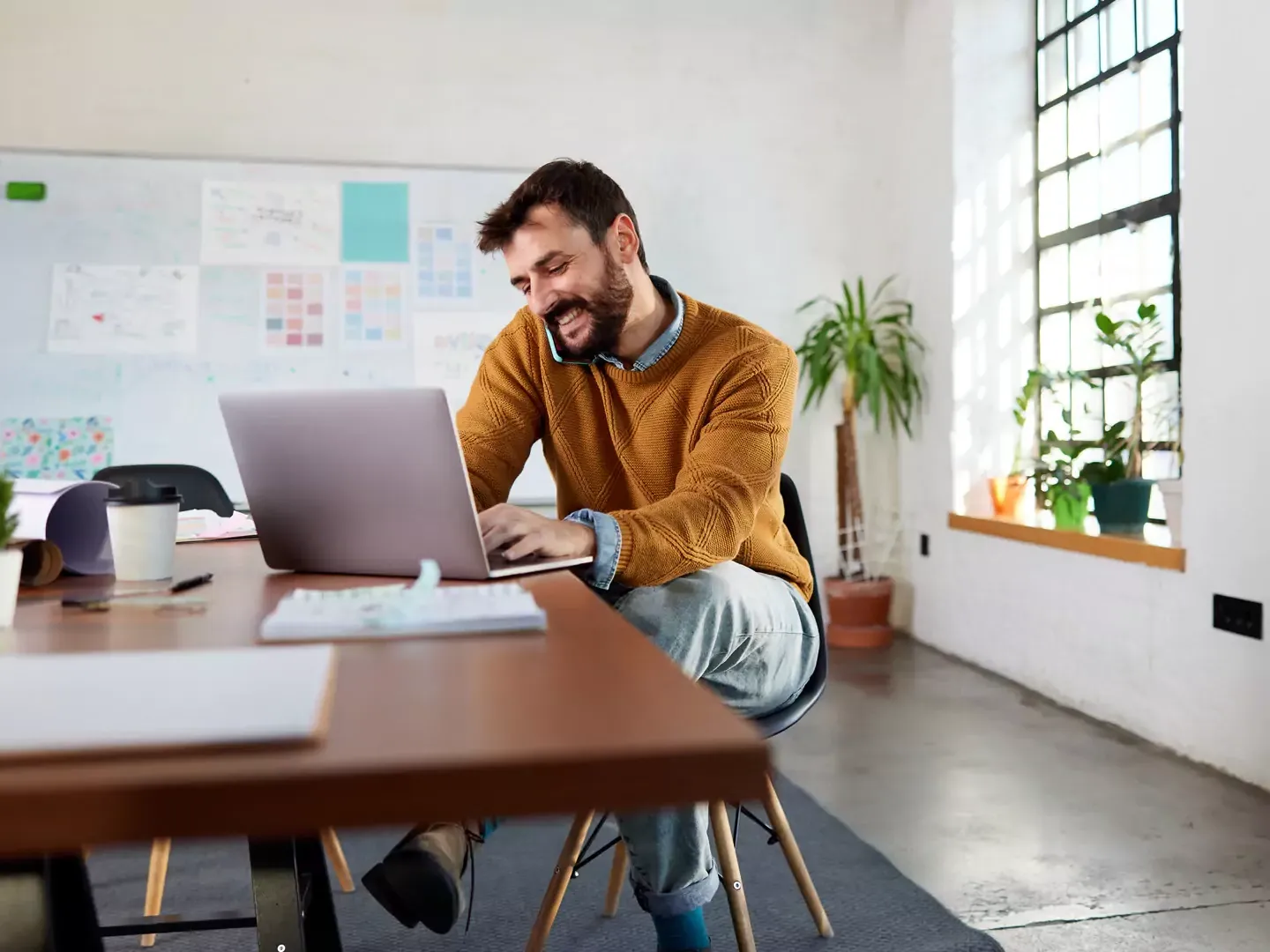 Man in yellow sweater using laptop at the office