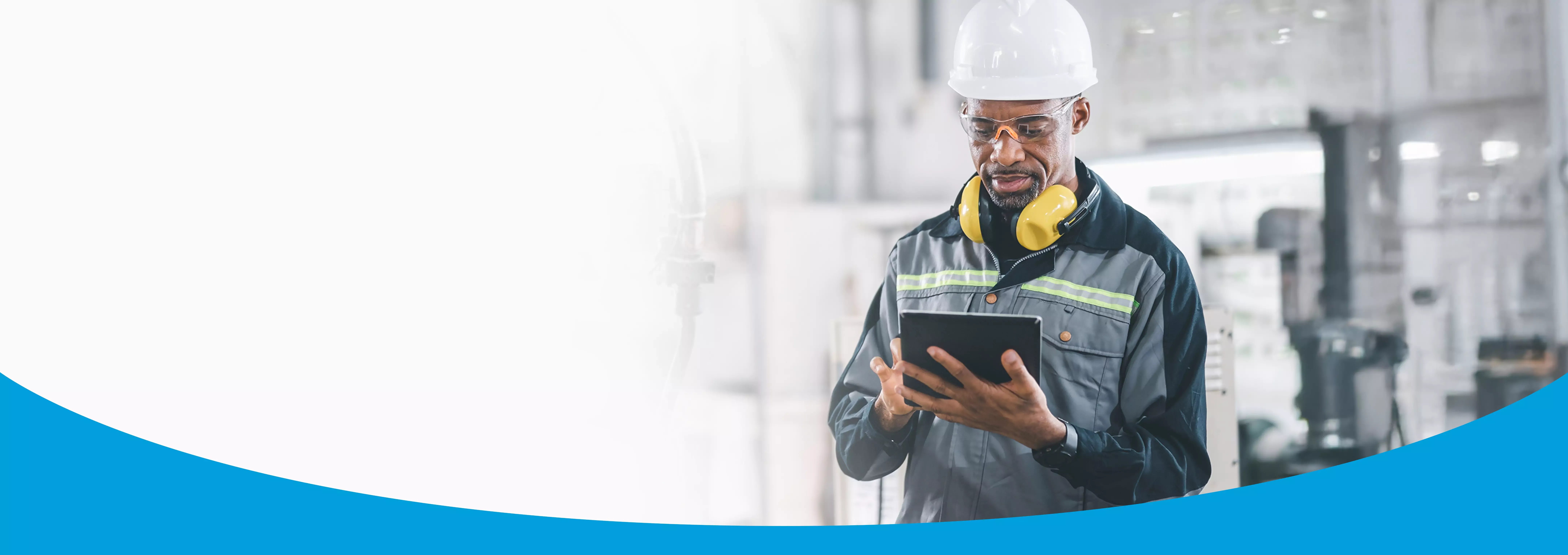 man with white hard hat using tablet at work