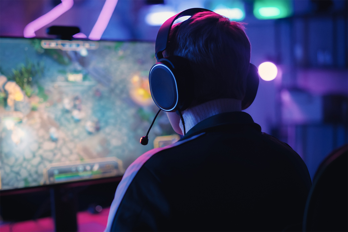 Man wearing headphones and gaming on a computer.