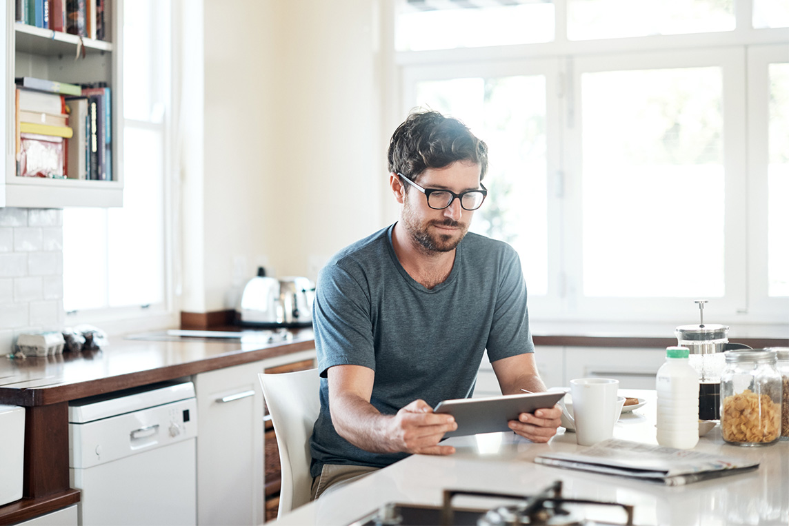 man using a digital tablet while having breakfast