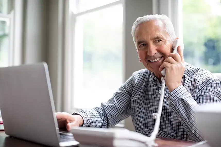 mature man using home phone and laptop
