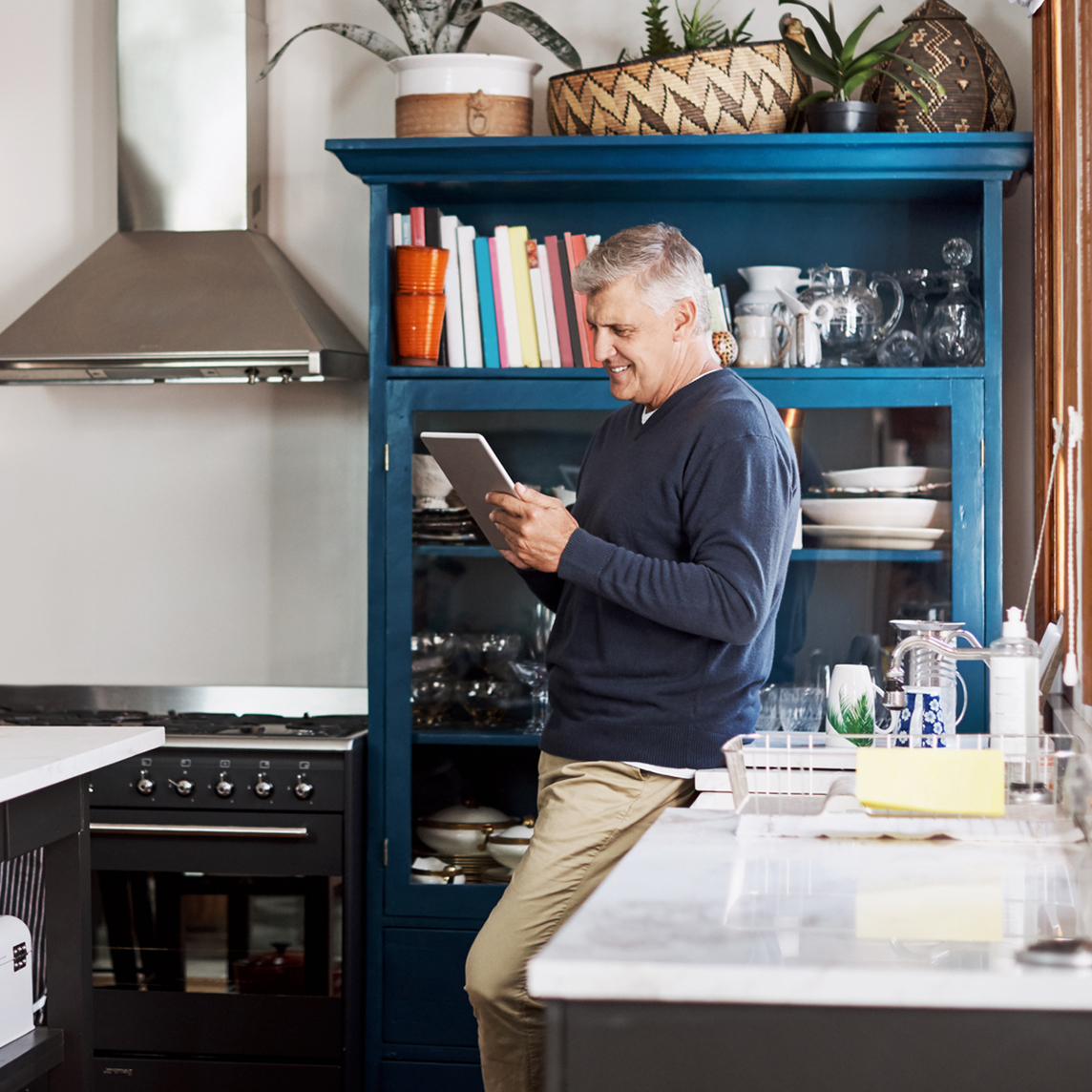 mature man using a digital tablet at home
