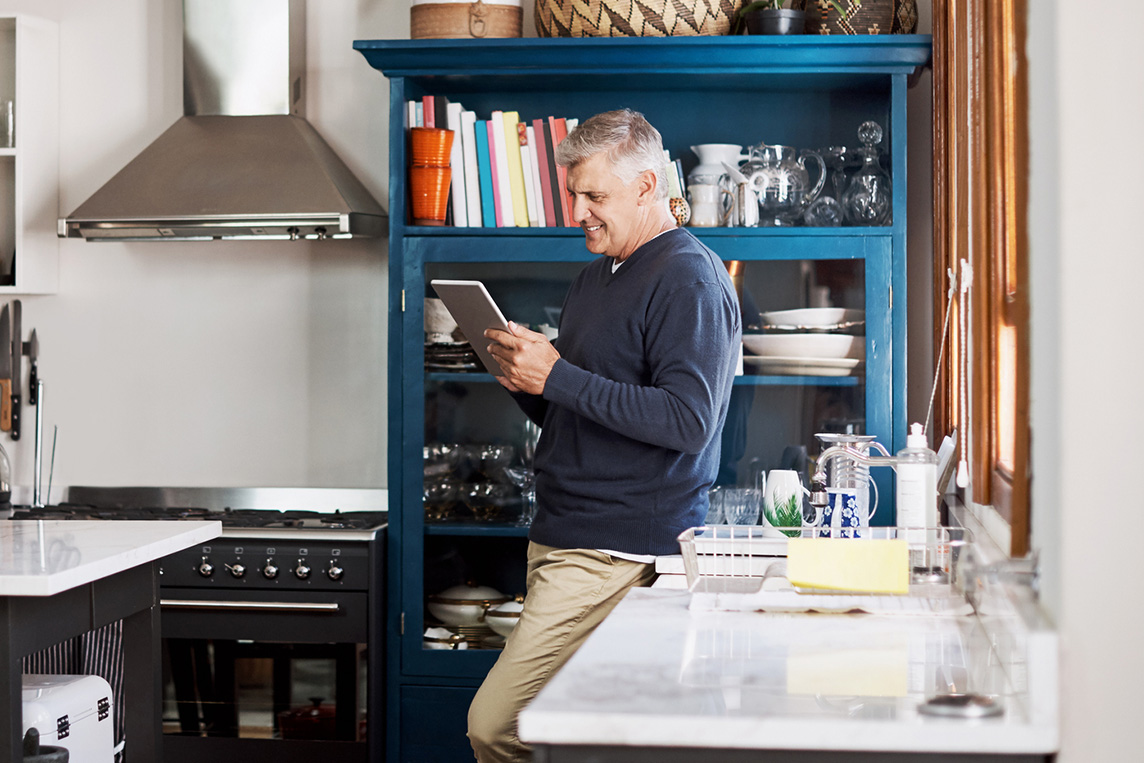 mature man using a digital tablet at home