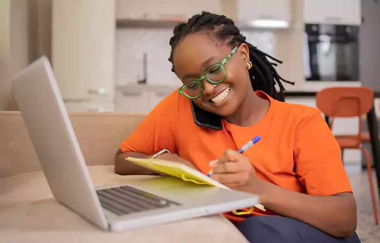 Happy woman uses laptop at home with fast, affordable internet.