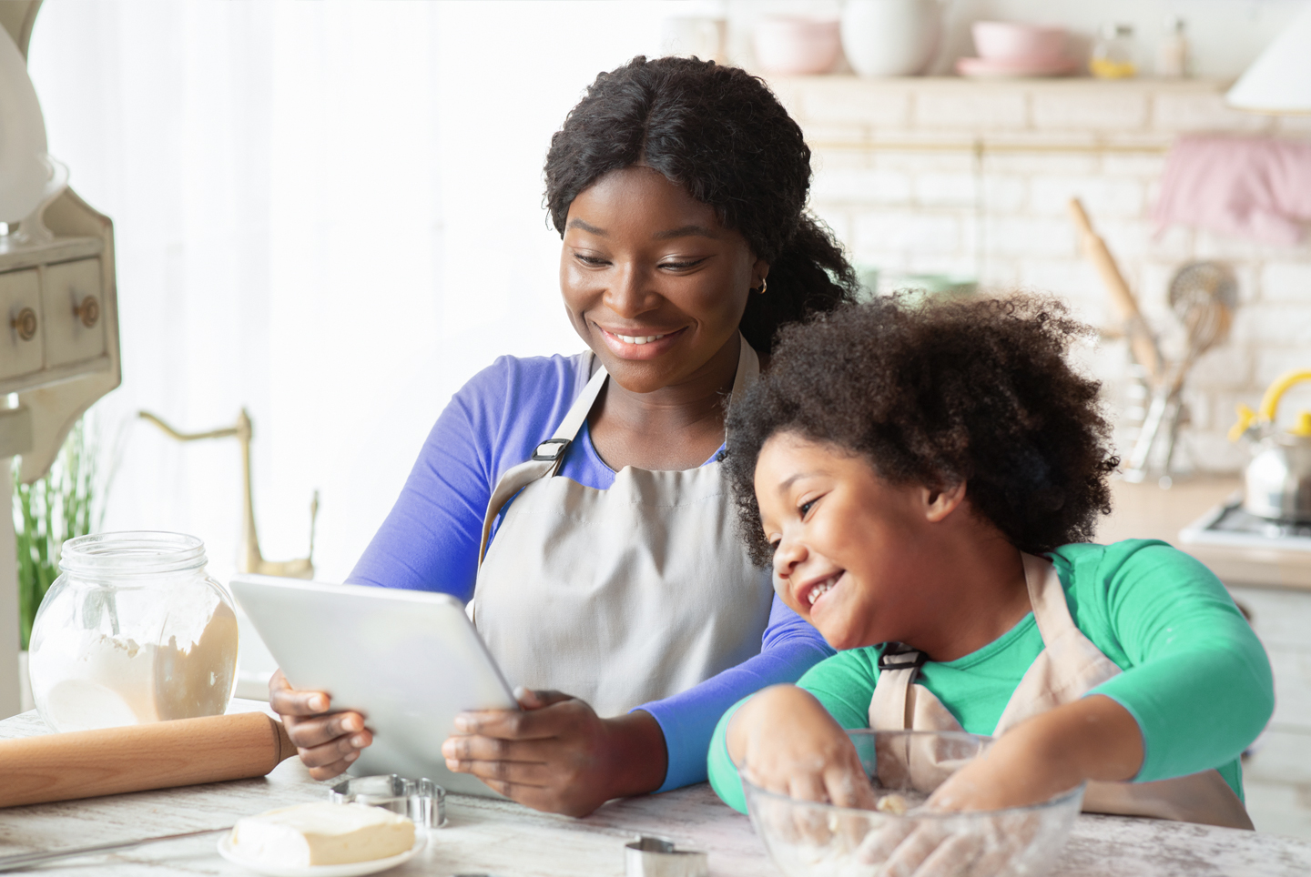 Mom and daughter watching a cooking show in the kitchen.