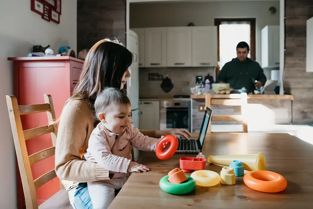 mom working on laptop at kitchen table with baby