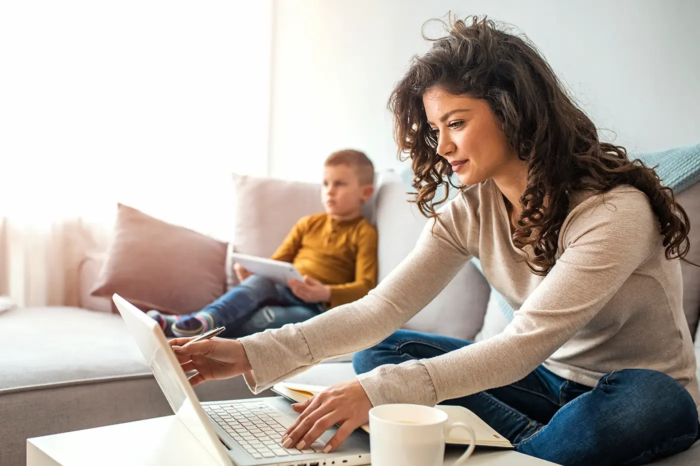 Mom working at home while son watches tv