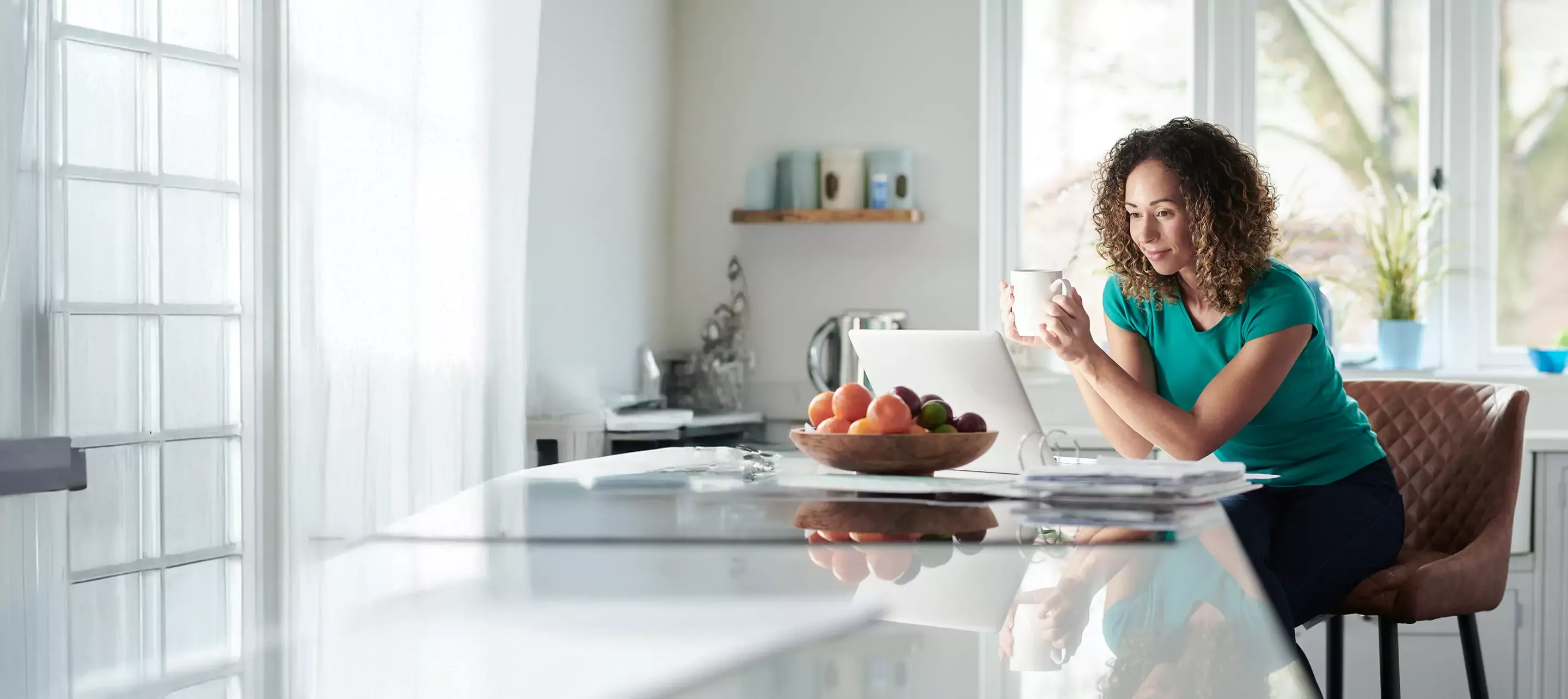 Woman sipping on morning coffee and enjoying a little internet too.