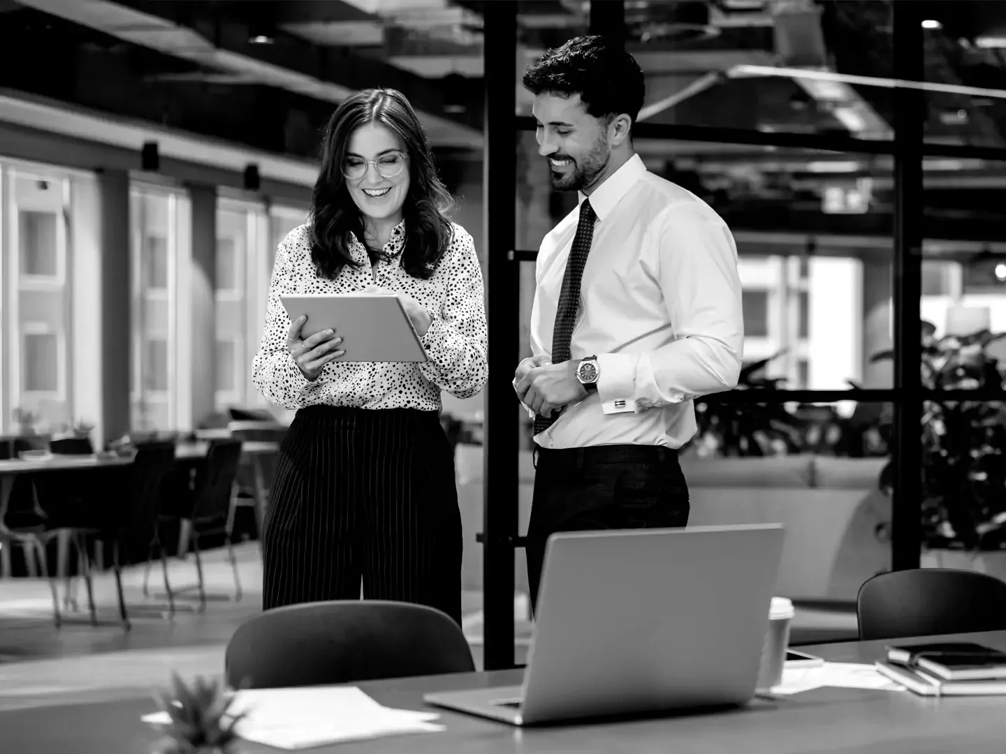 Two employees collaborating over a tablet in the office.