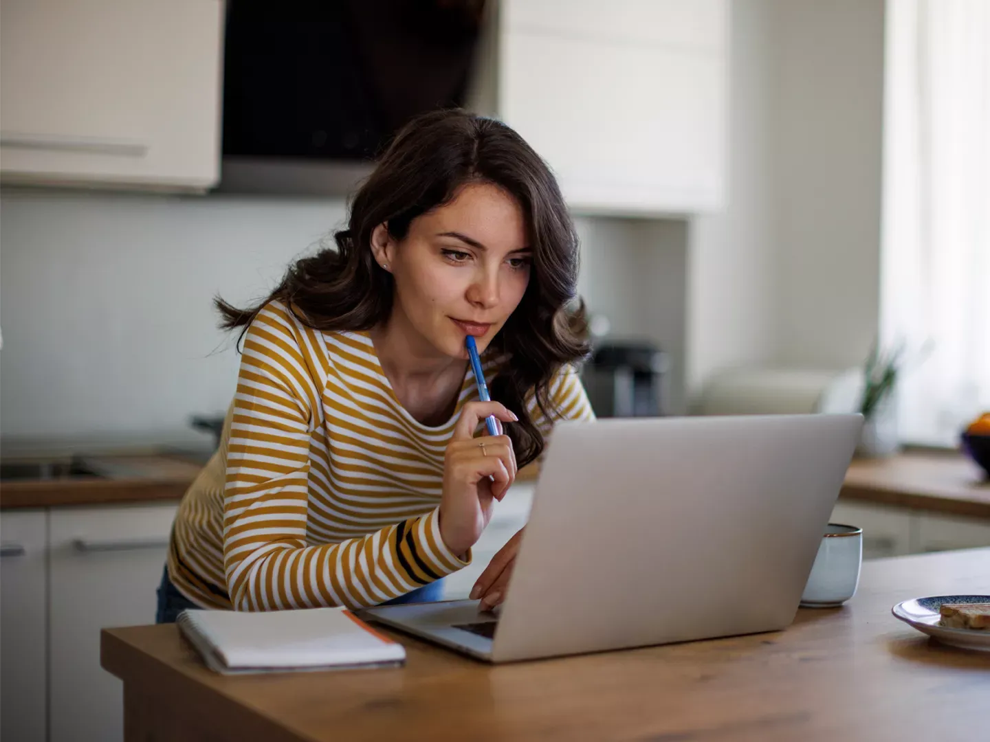 Woman thinking and looking into her laptop.