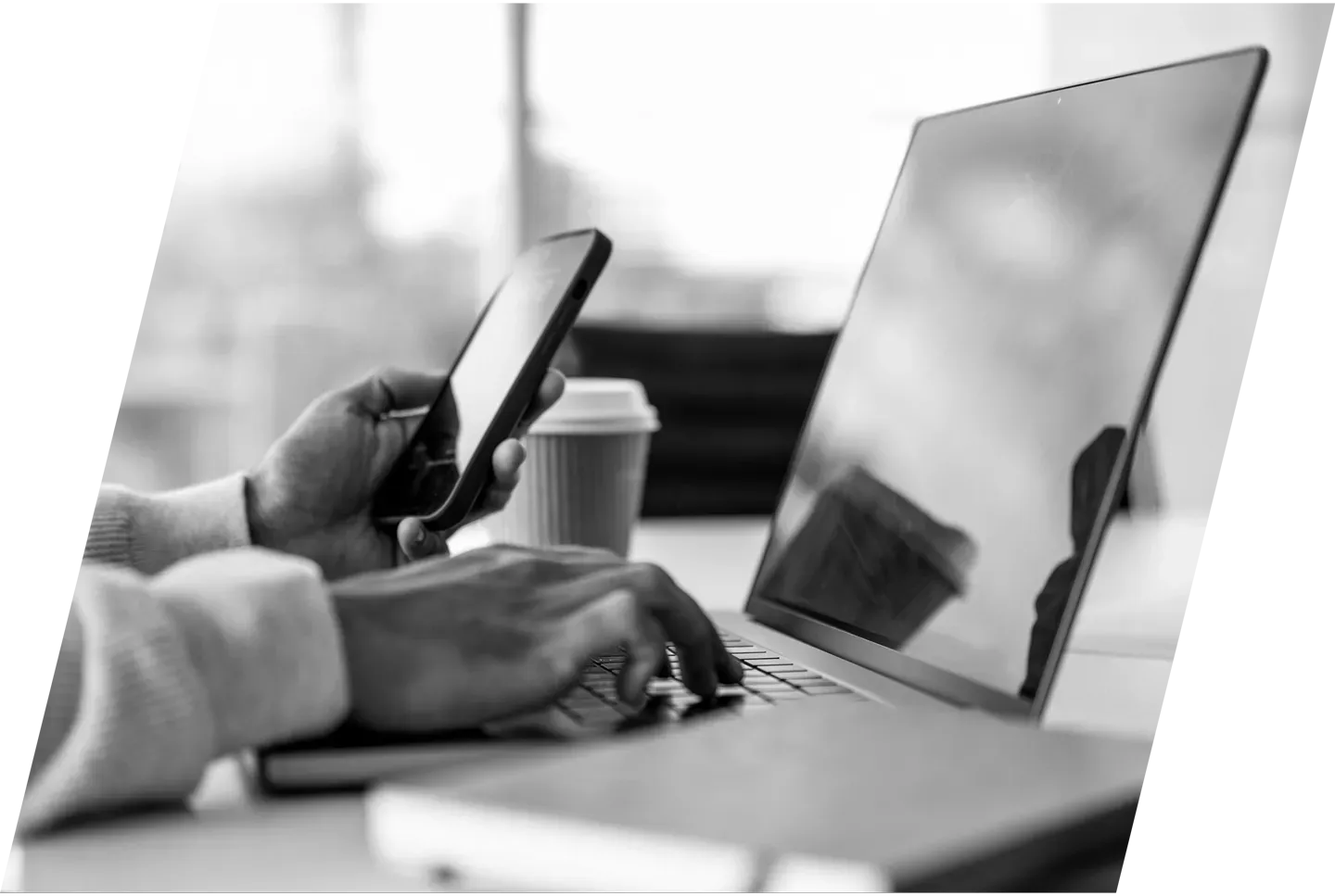 man typing on a laptop with a smartphone in his hand