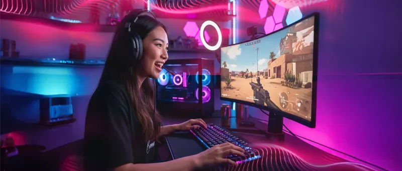 An excited girl playing online FPS games with magenta neon lighting.