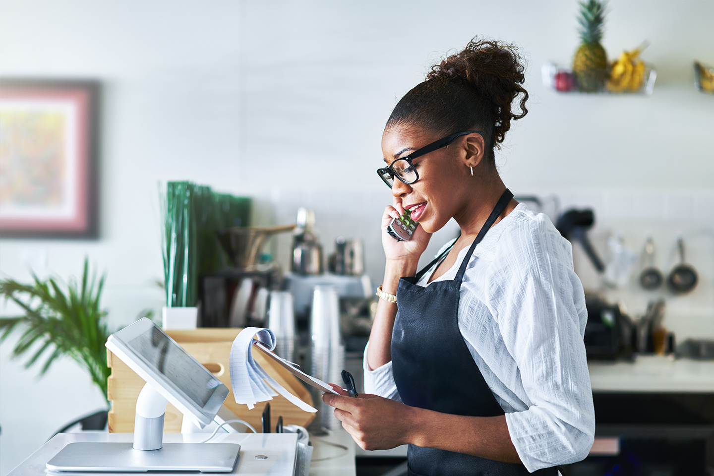 friendly waitress taking order on phone at restaurant and writing on notepad