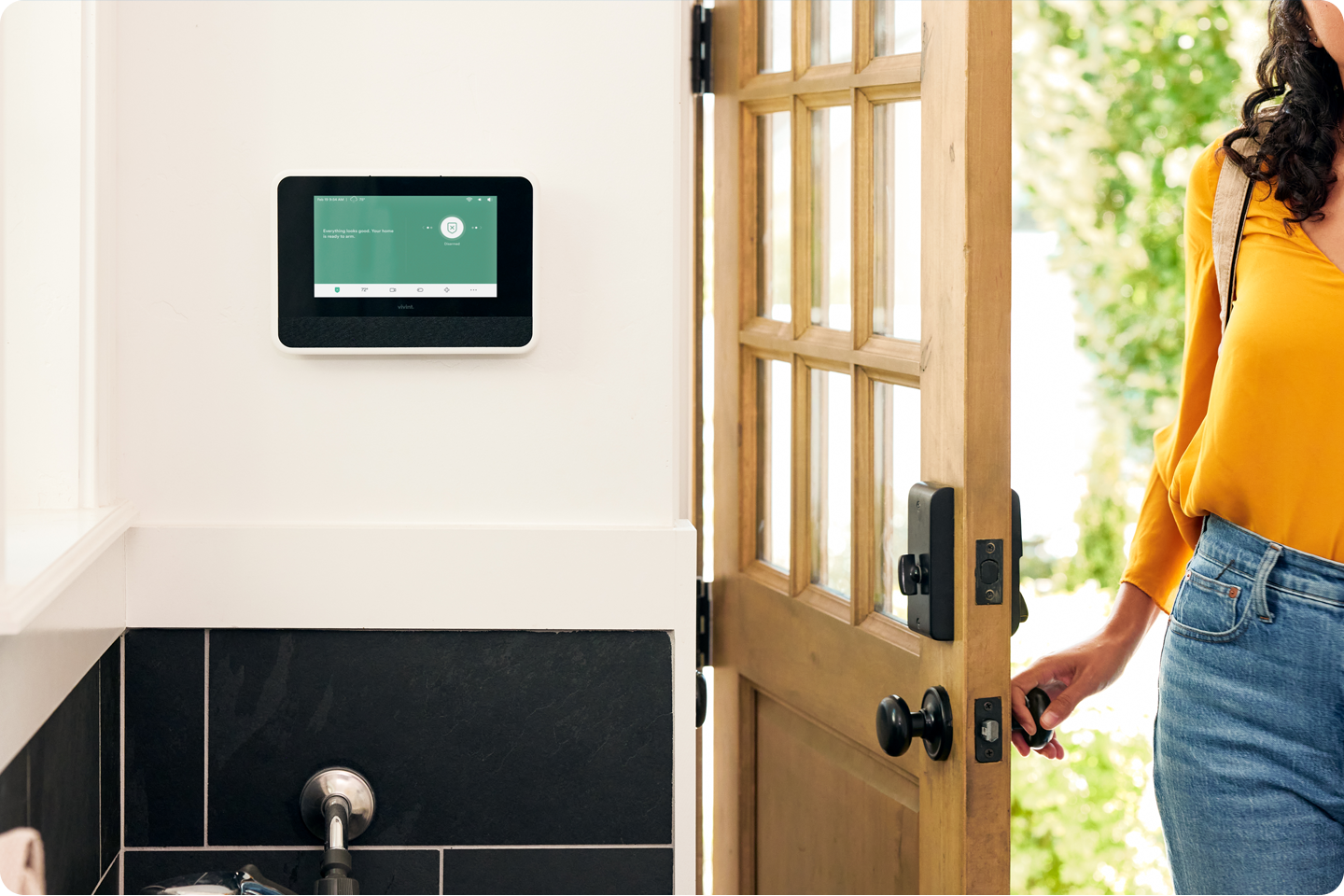 Woman opening front door with a Vivint Smart Hub next to the door
