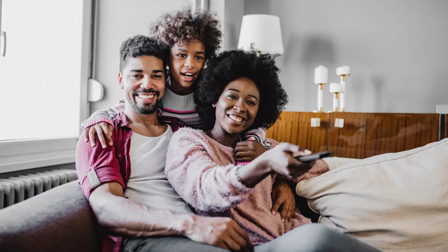 Cute family of 3 embracing, smiling, and enjoying their favorite show