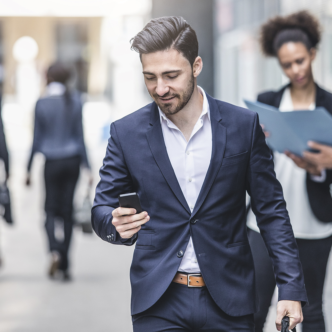 Businessman walking from office while texting on his phone