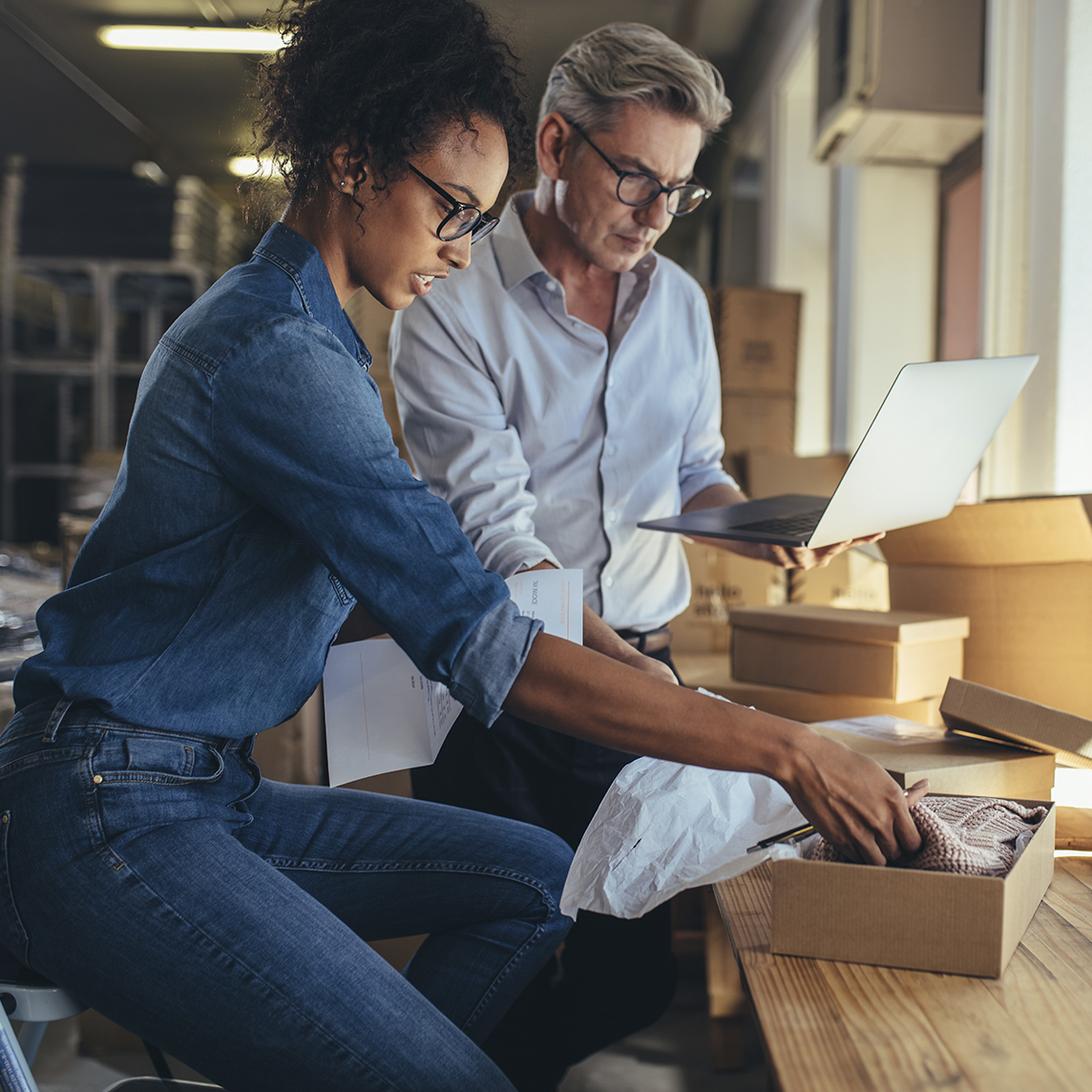 Two coworkers packaging up items at desk