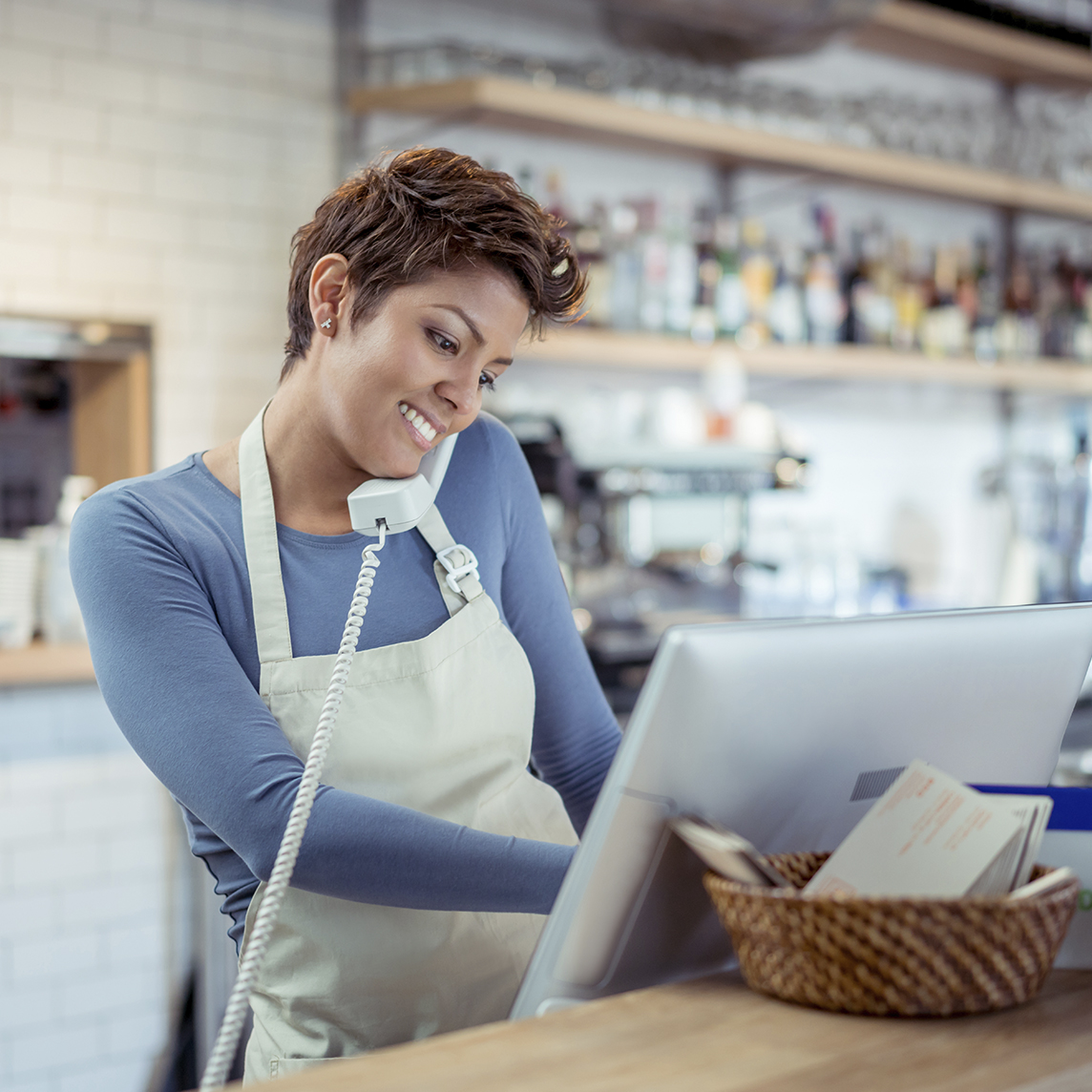Woman working at counter while using the phone