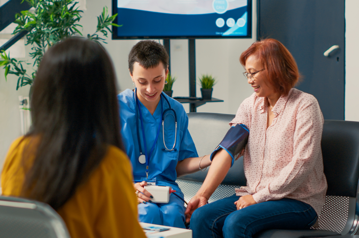 A nurse helps a patient check vitals in a waiting room.