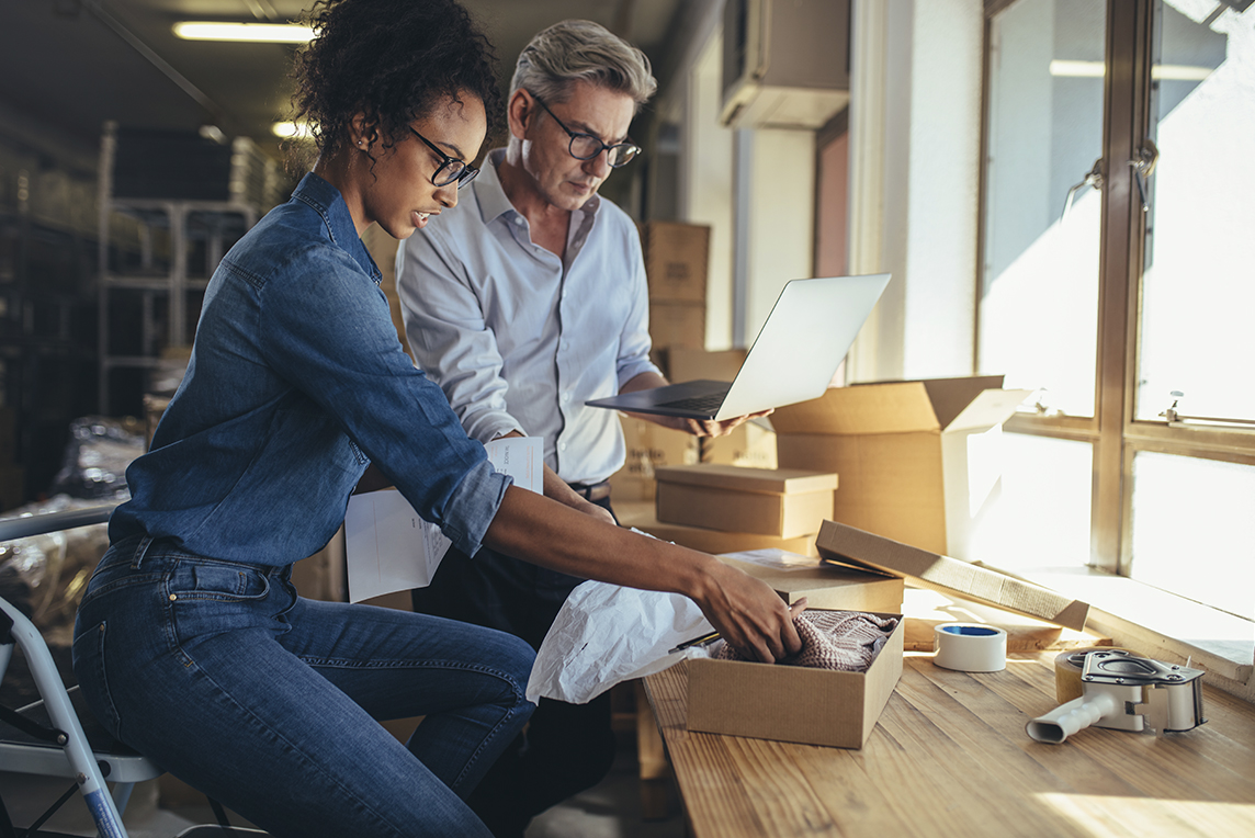 Two coworkers packaging up items at desk