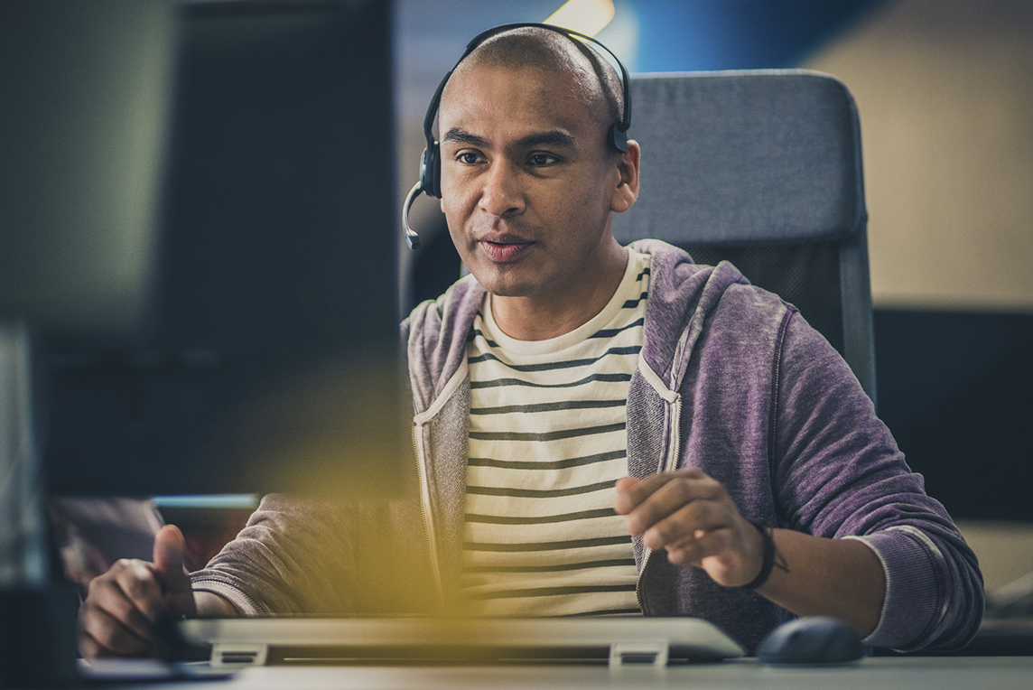 Man on computer talking on headset