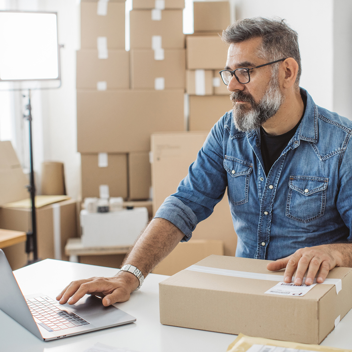 Business owner entering packaging data into laptop