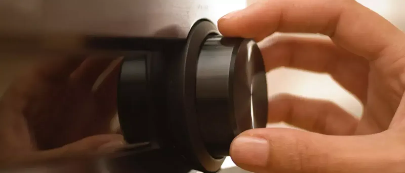 Hand turning up volume dial on TV