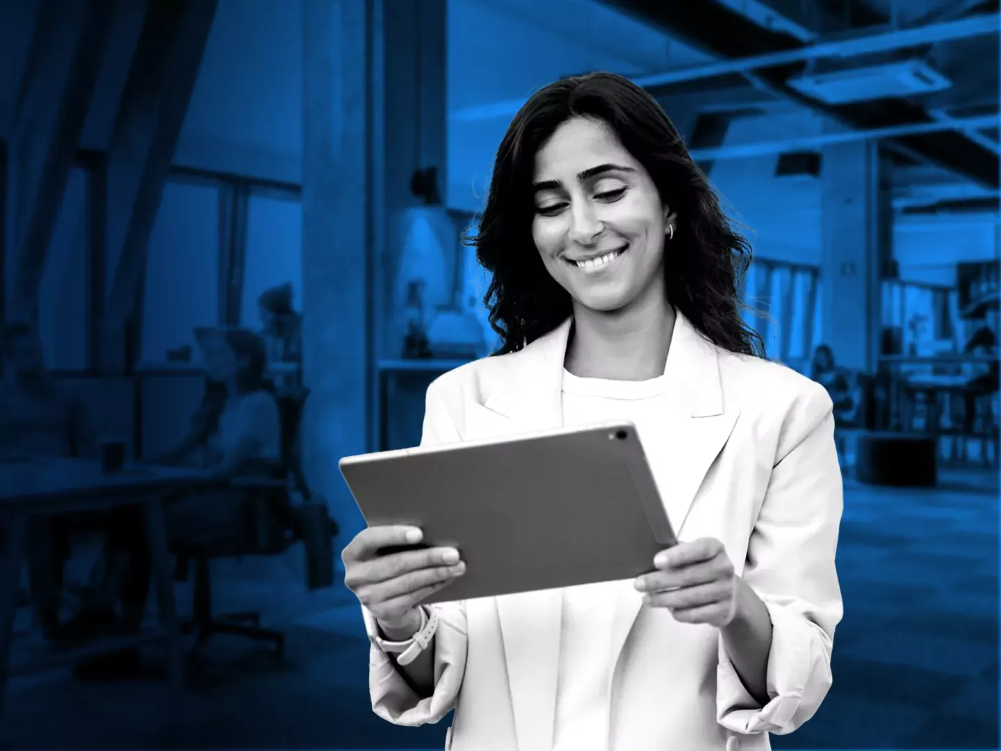 Smiling woman in a white suit coat looking at a tablet in her hands