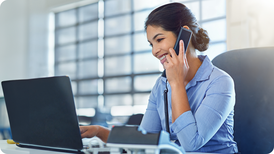 A lady talks on the phone with a VoIP system.