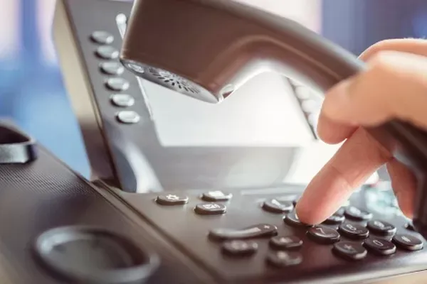 Close up image of a person using their office phone.