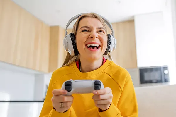 Happy woman plays video games at home with fast fiber internet
