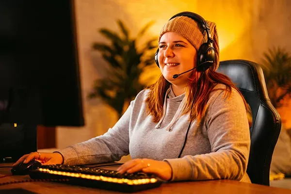Happy woman wearing beanie games on a computer at home