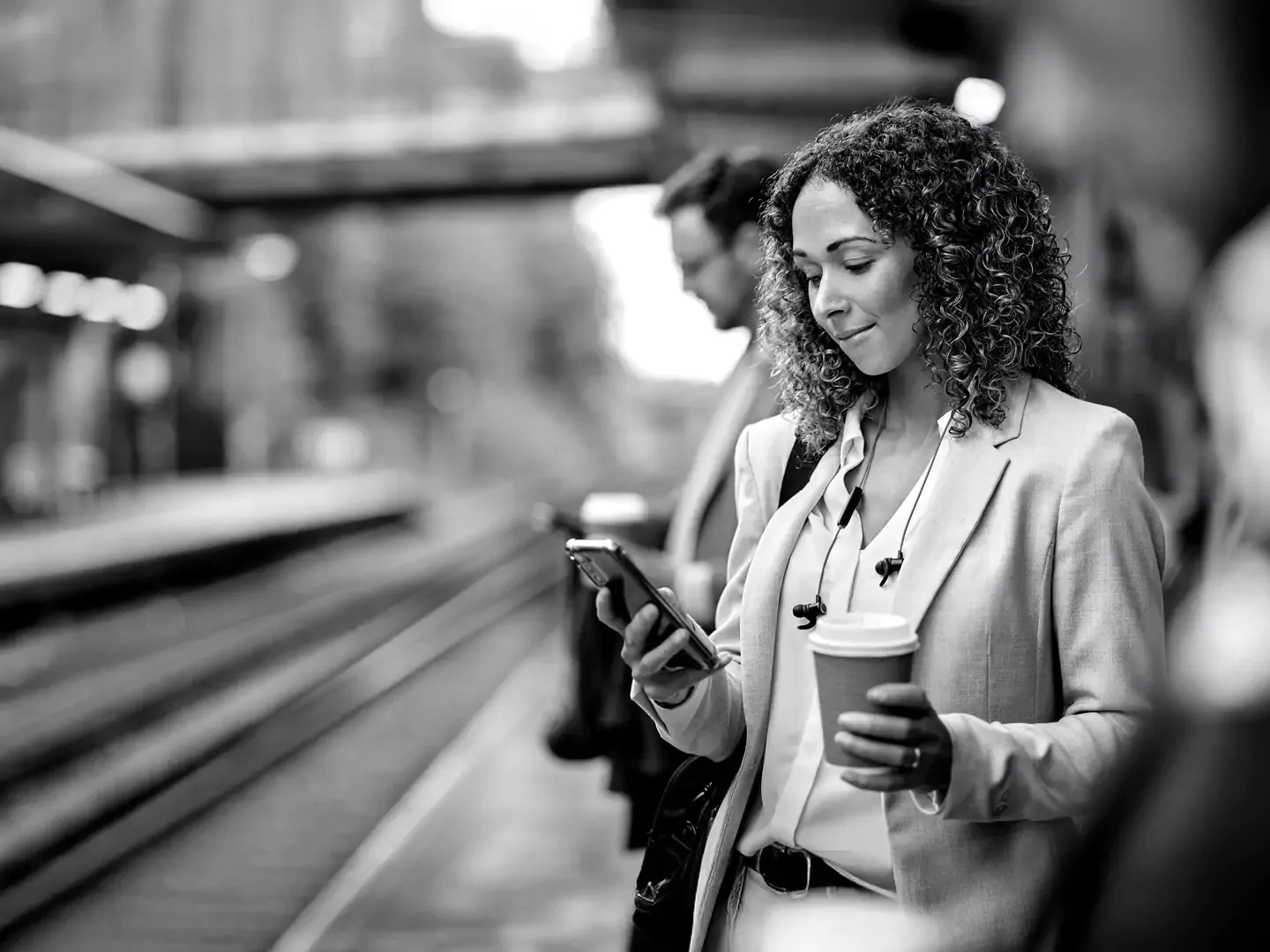 Woman using a cellphone for business while out and waiting for a train at the train station.