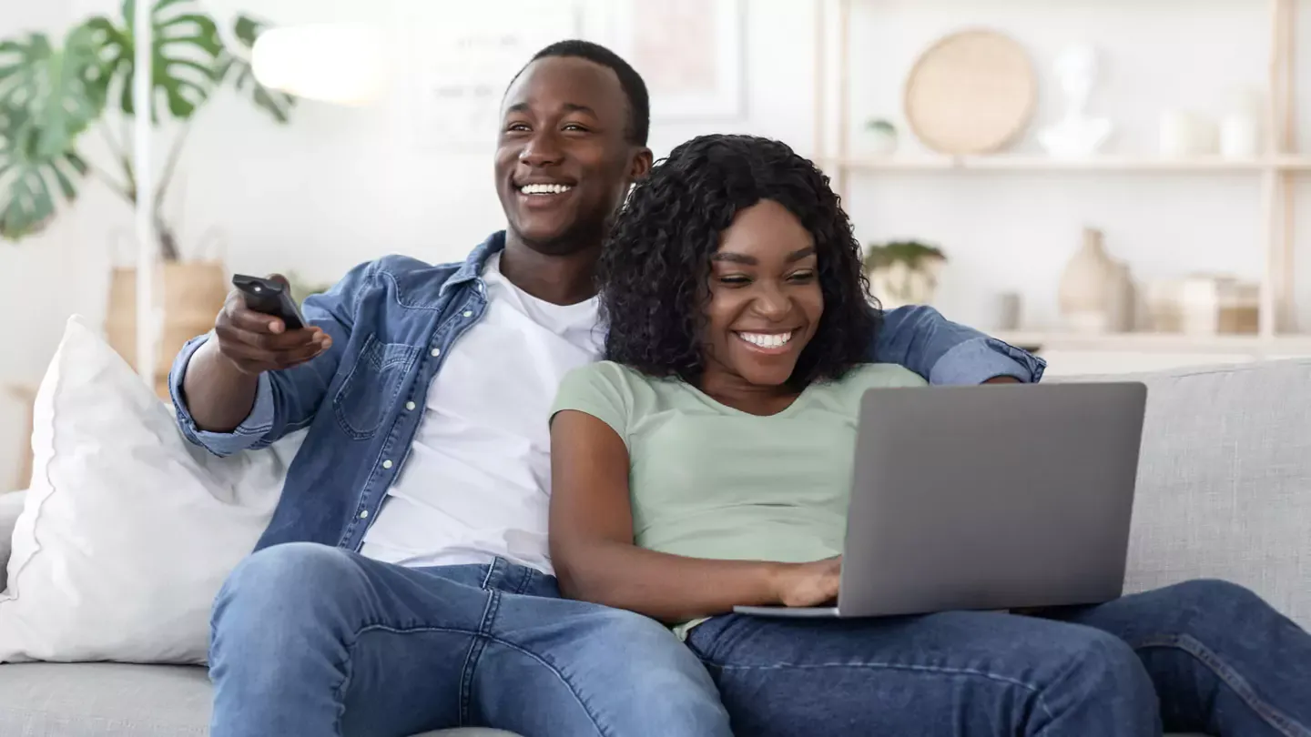 Couple watching TV and using a laptop