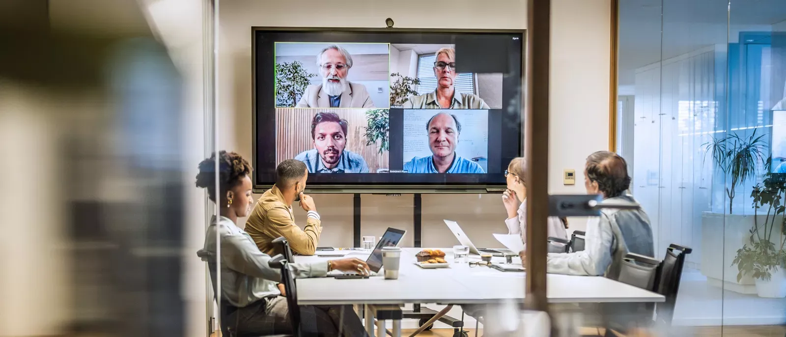 People in s small business conference room, they are having a video call with customers.