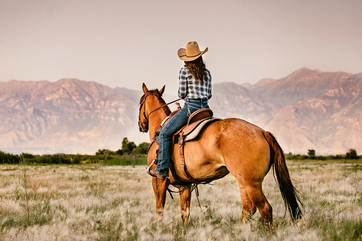 Cowgirl riding horse with mountain backdrop