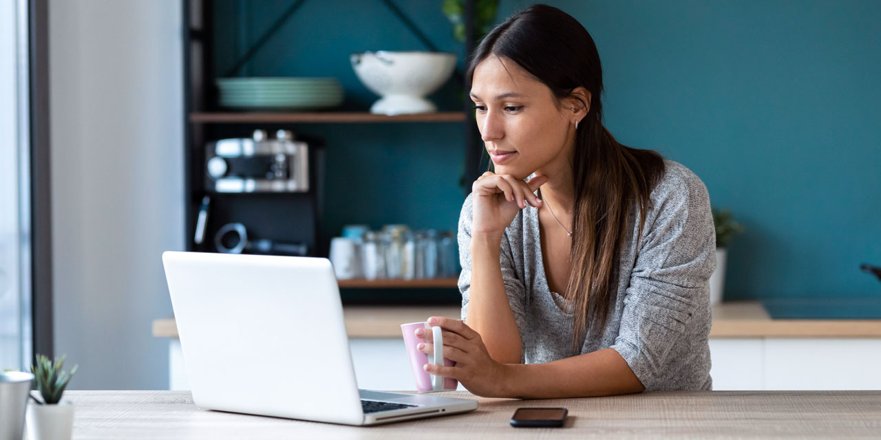 woman watching a show in her kitchen on her laptop using CenturyLink internet
