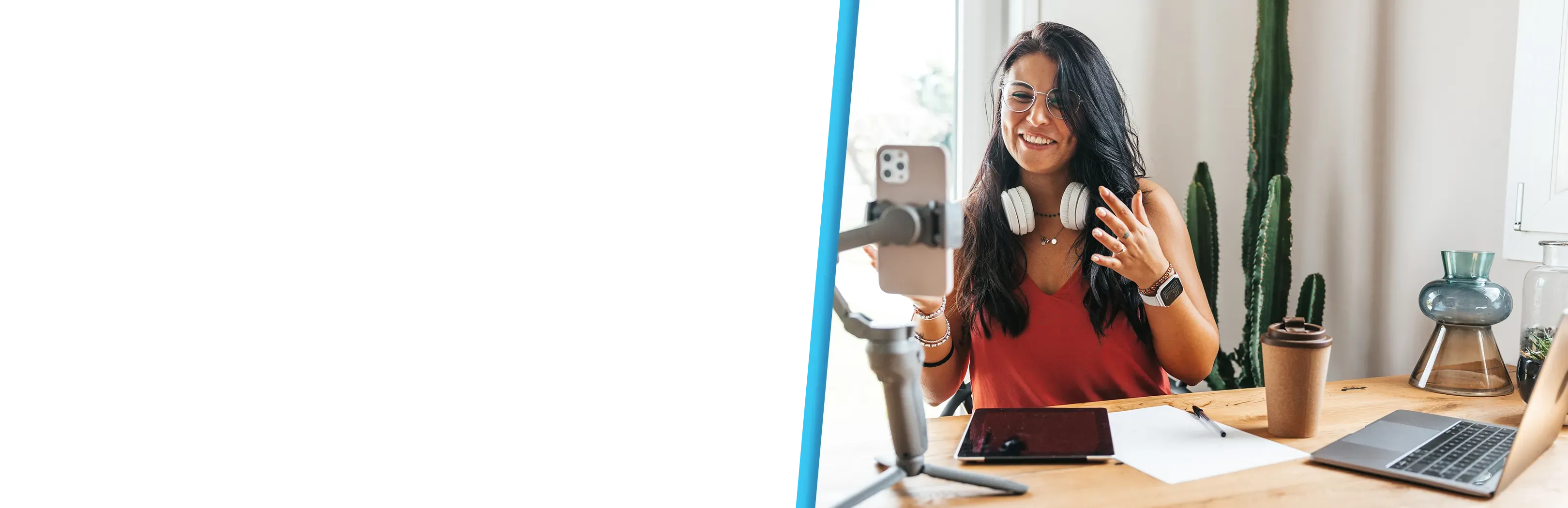 A smiling woman records herself on a phone gimbal at a desk with cacti.