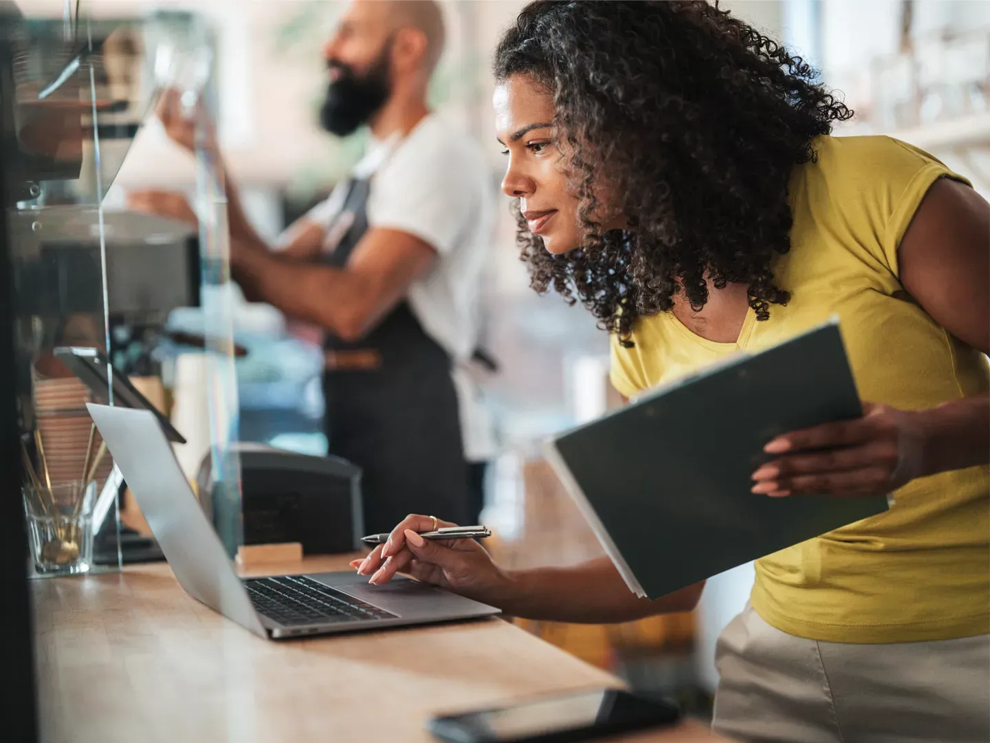 Woman in yellow shirt using laptop at the business.