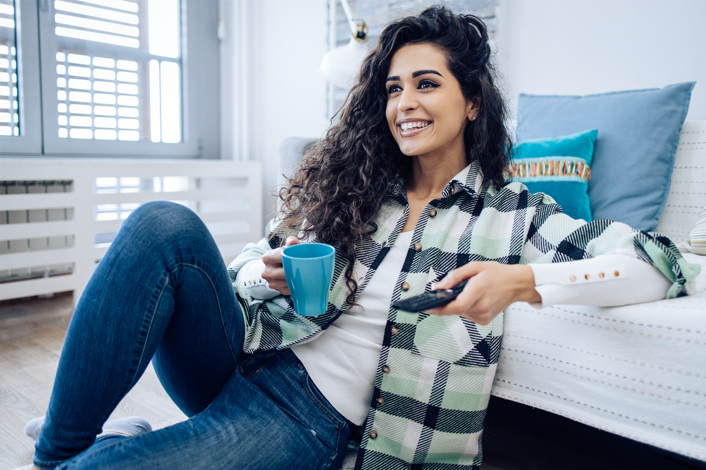 woman watching TV and enjoying coffee at home