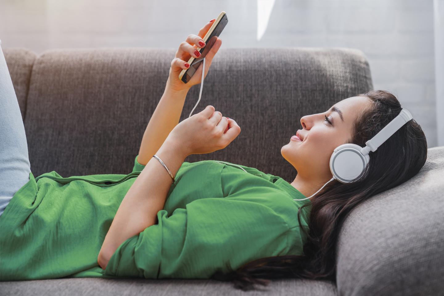 Mujer con auriculares escuchando sus canciones favoritas en su smartphone.
Woman with headphones listening to her favorite songs on her smartphone.