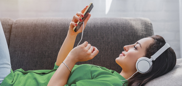 Mujer con auriculares escuchando sus canciones favoritas en su smartphone.
Woman with headphones listening to her favorite songs on her smartphone.